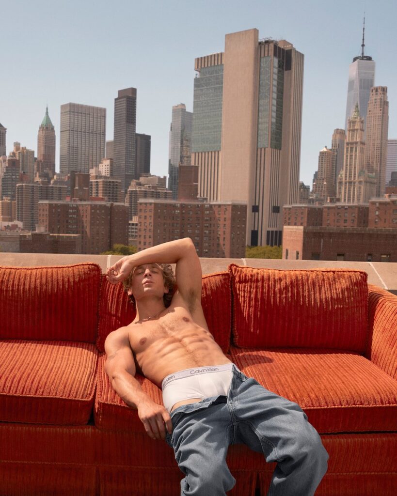 Jeremy Allen White Heats Up Spring 2024 in Calvin Klein's Underwear Campaign, posing for CK on a couch wearng white sexy yndergarment 